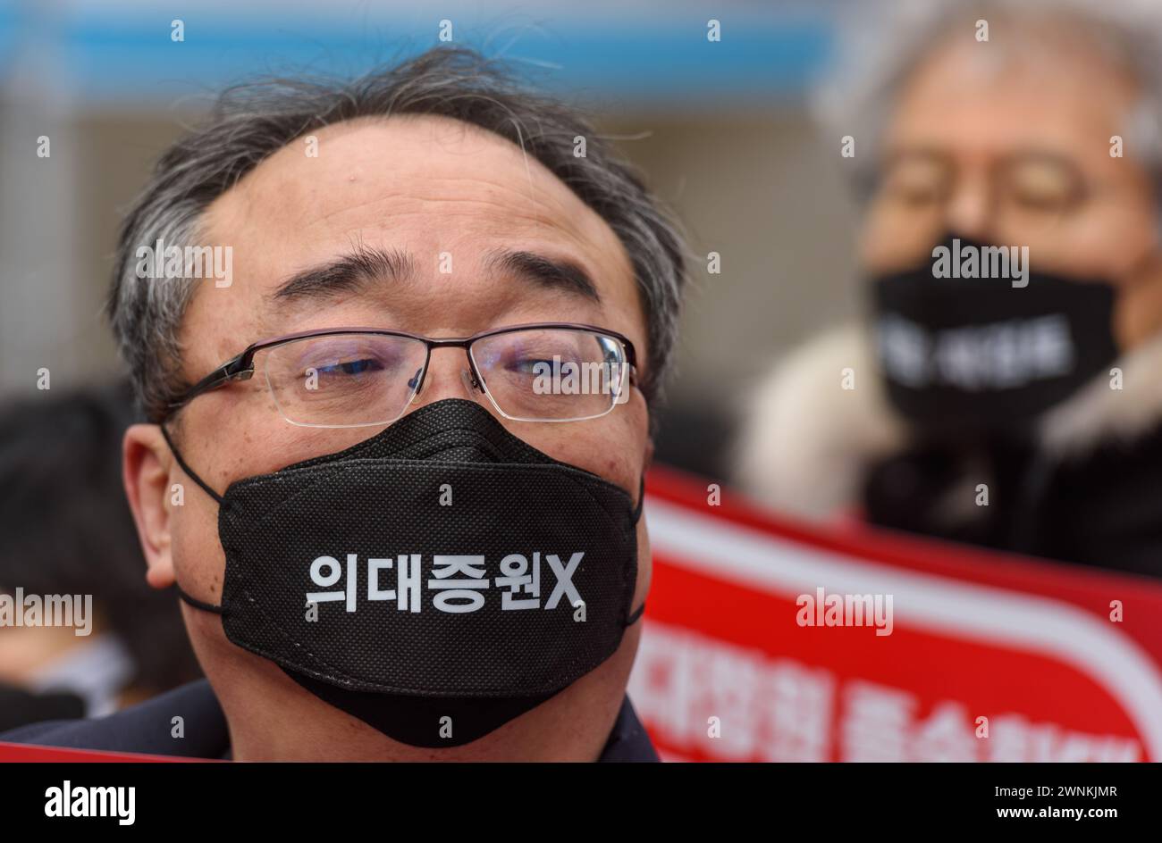 A South Korean doctor wears a mask written on 'increasing medical school admissions X' during the demonstration. Thousands of senior doctors held a rally in Seoul against the government's medical school quota hike plan as Prime Minister Han Duck-soo hinted at the possible suspension of medical licenses for striking trainee doctors. The rally by members of the Korean Medical Association (KMA), the biggest medical lobby group, came as thousands of trainee doctors have remained off their jobs at general hospitals for the 13th day, protesting the plan to add 2,000 more medical school seats startin Stock Photo