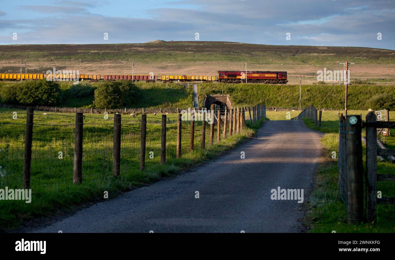 EWS class 66 locomotive 66186 hauling train carrying materials for Network Rail along the west coast mainline in Cumbria Stock Photo