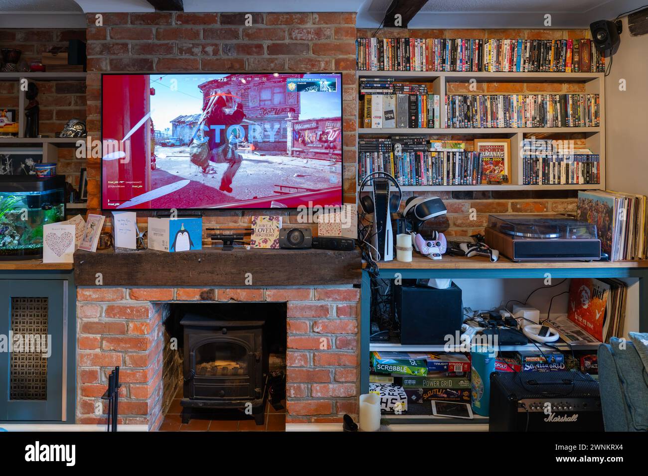 Call of Duty Black Ops Cold War being played on a PS5 with the victory screen showing on a tv screen in a UK lounge, with physical media on shelves Stock Photo
