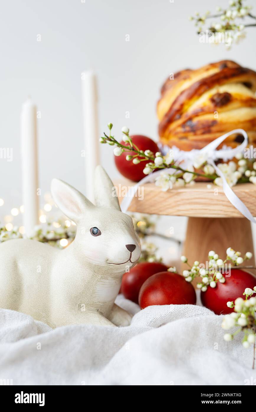 Festive table setting with ceramic bunny, red eggs, candles and Easter pastries. Easter holiday concept Stock Photo