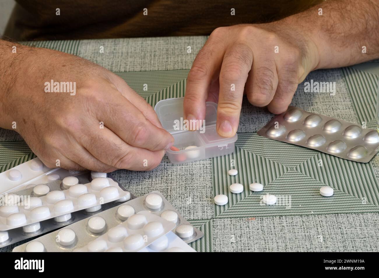 There are pills on the table. Man's hands puts pills in a box. Stock Photo