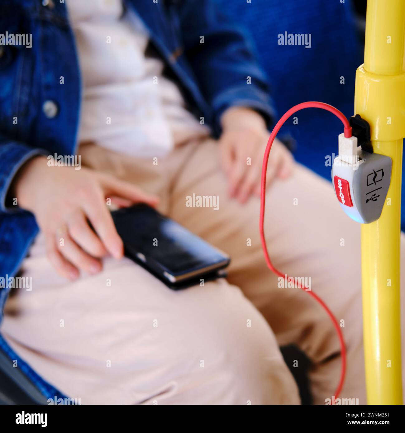 A man with a phone on a bus seat. Device for charging the phone in ...