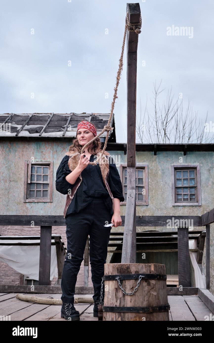 A female robber holds a gallows noose and a knife in her hand at the execution site Stock Photo