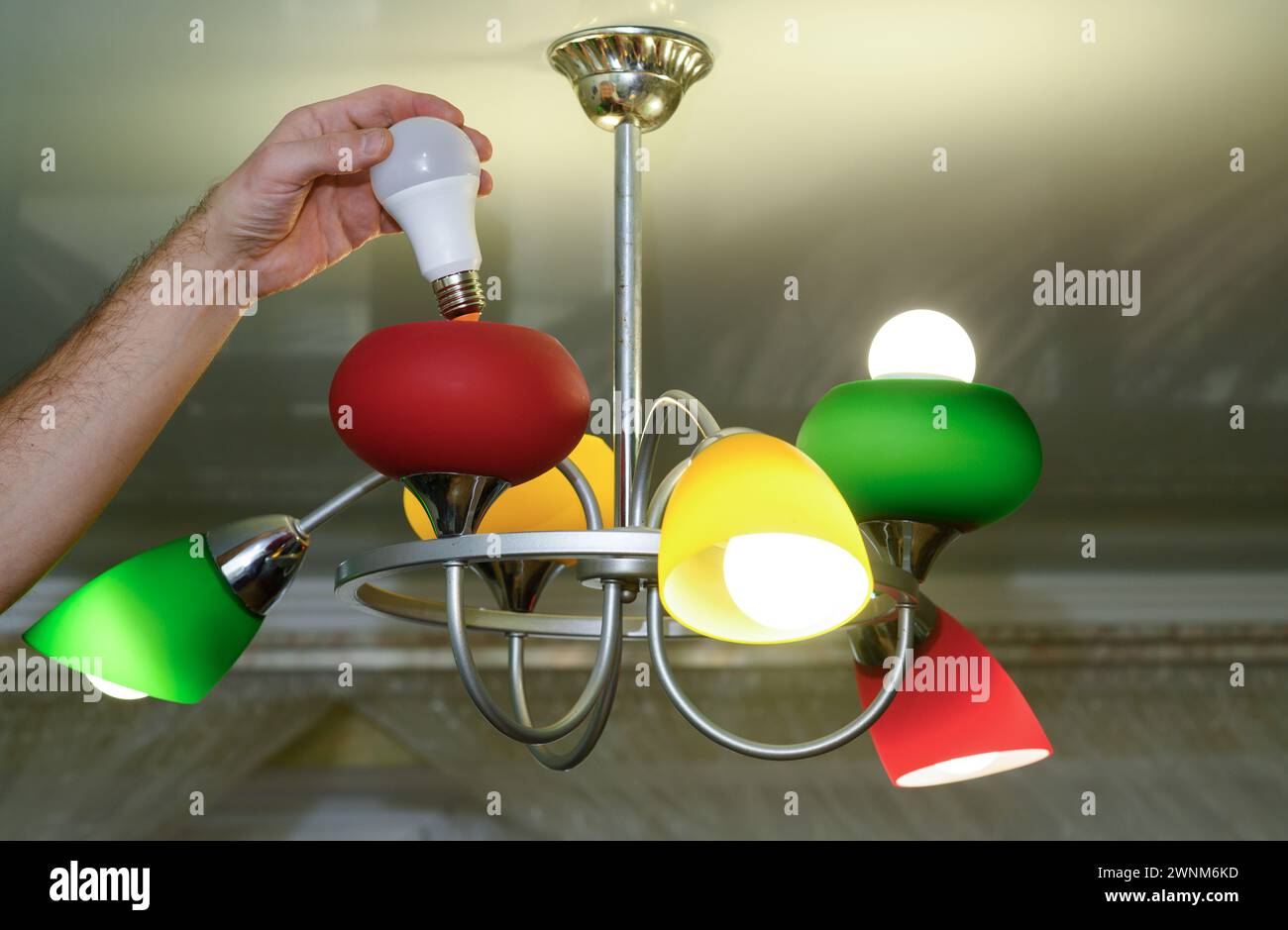 replacing the light bulb in the chandelier. LED lamp. Stock Photo