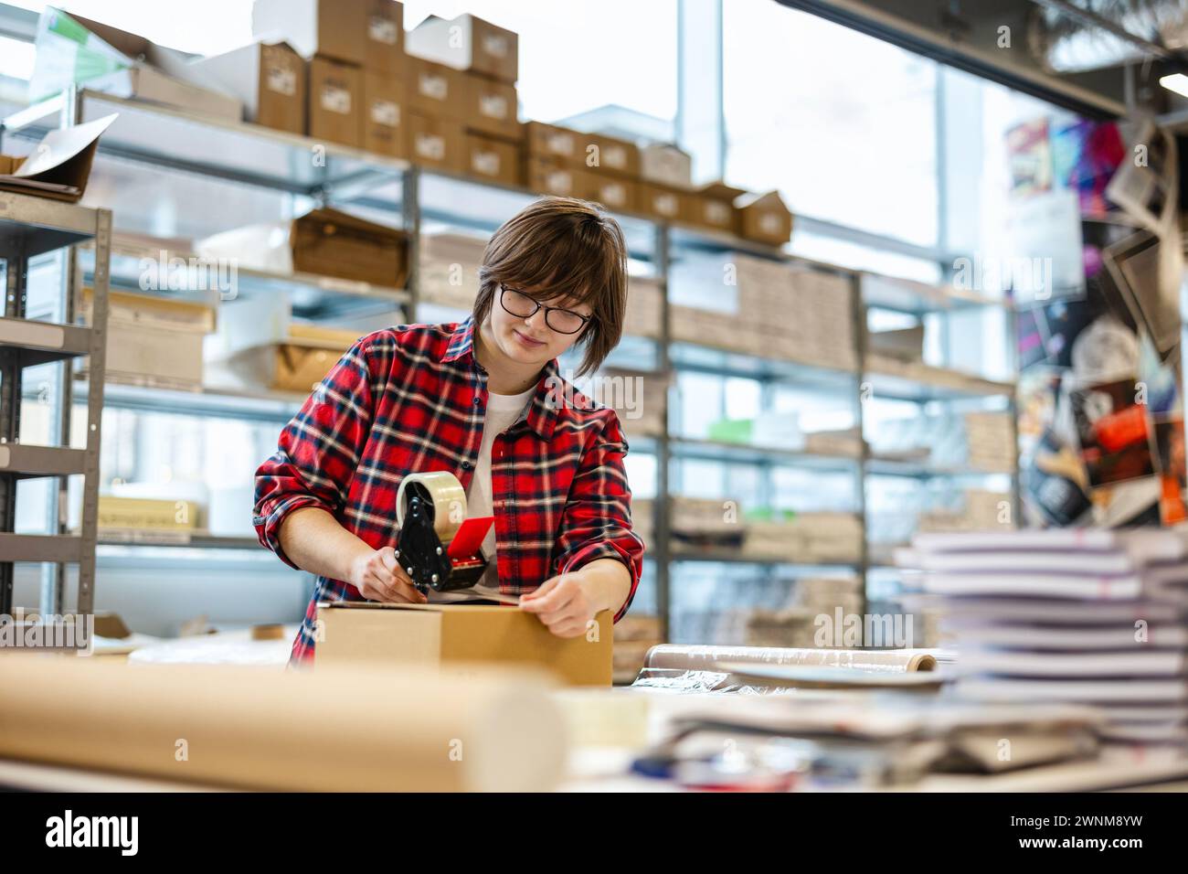 Female Worker Taping Cardboard Box Stock Photo