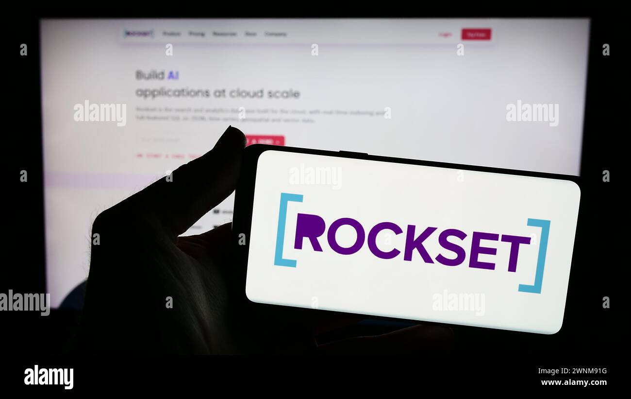 Person holding smartphone with logo of US analytics database company Rockset Inc. in front of website. Focus on phone display. Stock Photo
