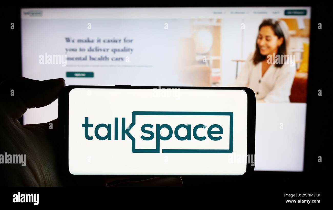 Person holding cellphone with logo of US online psychotherapy company Talkspace Inc. in front of business webpage. Focus on phone display. Stock Photo