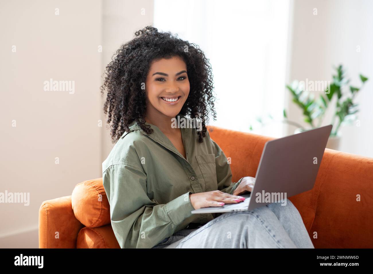 Happy young programmer black woman works on laptop at home Stock Photo