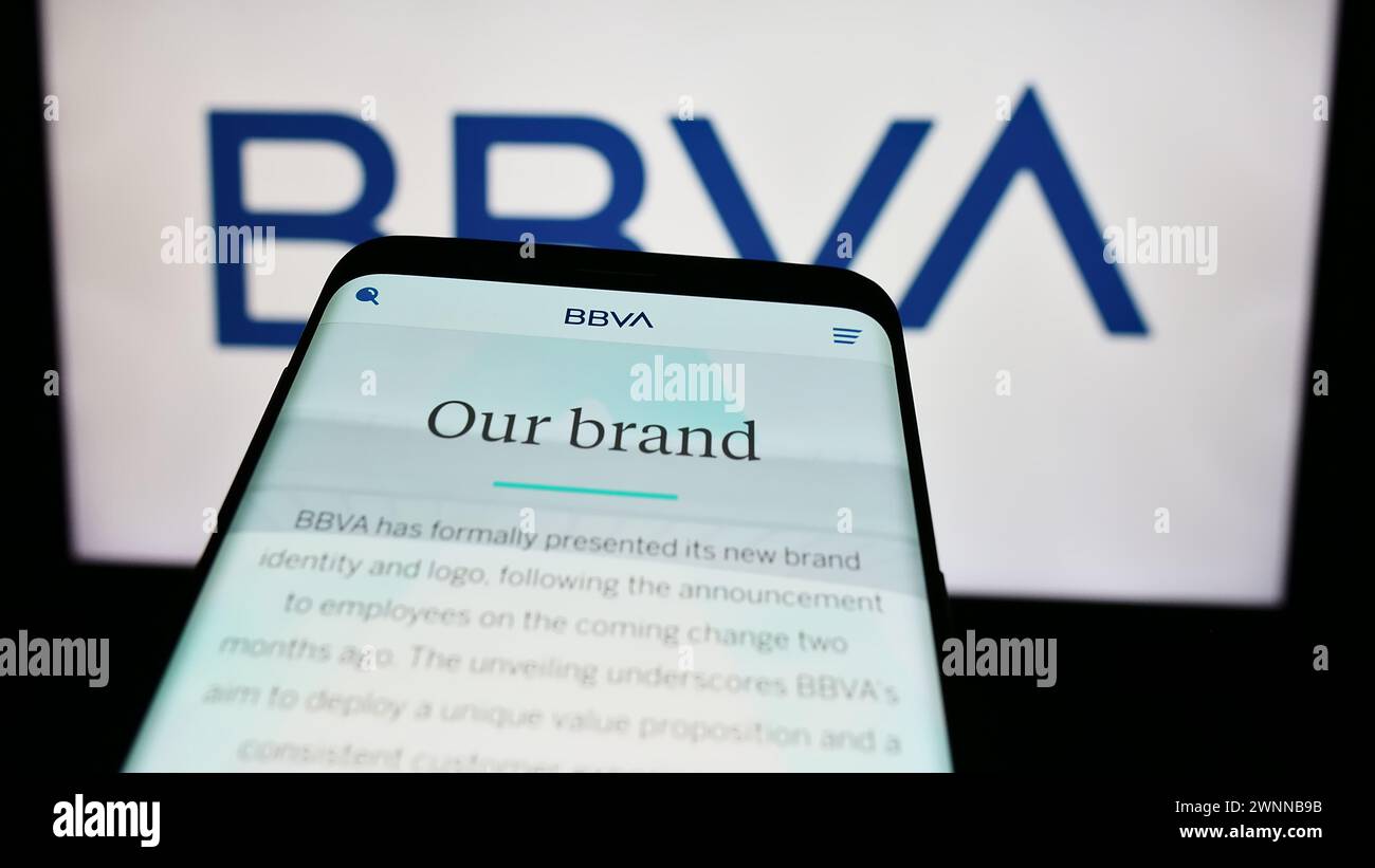 Mobile phone with website of company Banco Bilbao Vizcaya Argentaria S.A. (BBVA) in front of business logo. Focus on top-left of phone display. Stock Photo