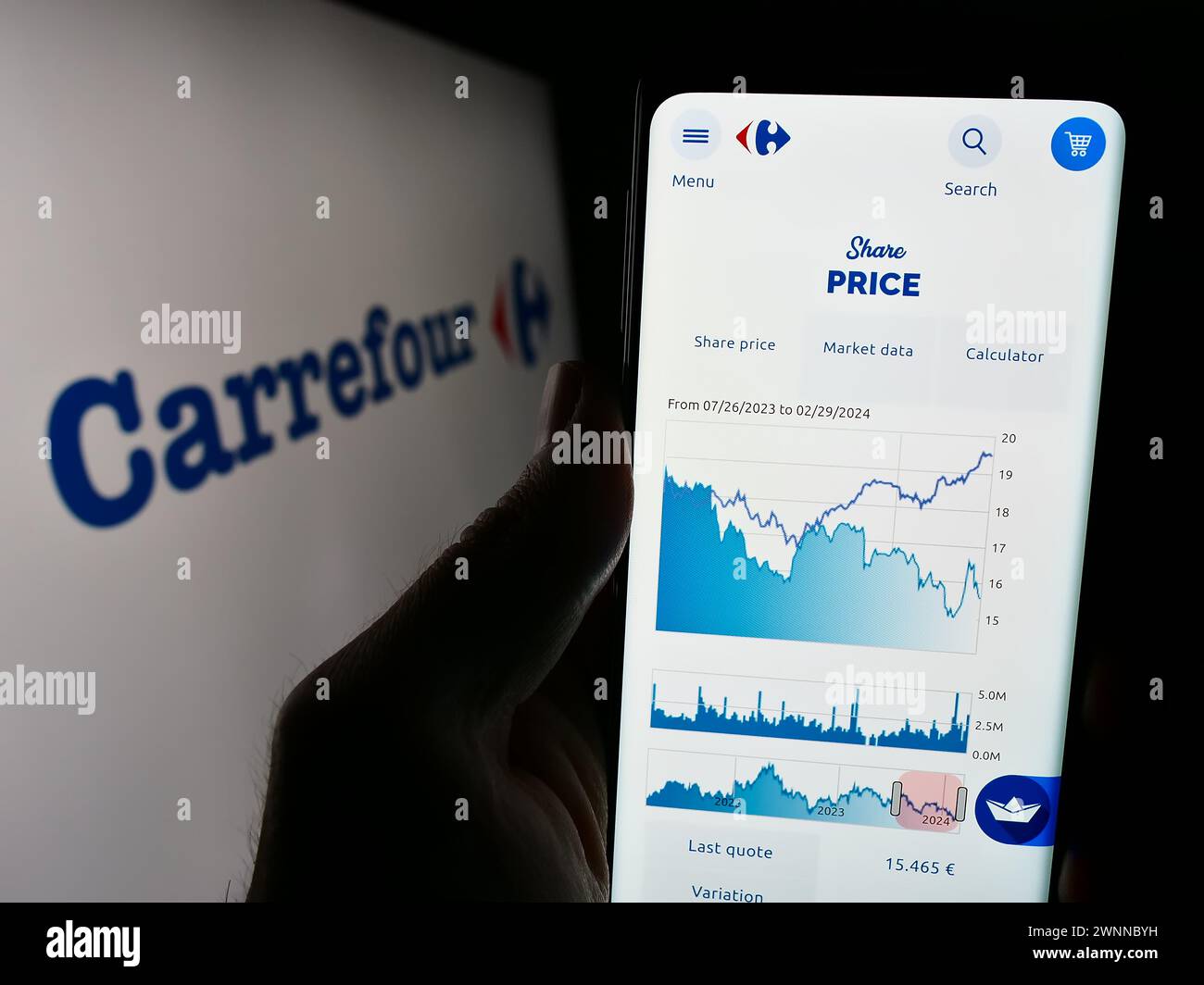 Person holding cellphone with webpage of French retail company Carrefour S.A. in front of business logo. Focus on center of phone display. Stock Photo