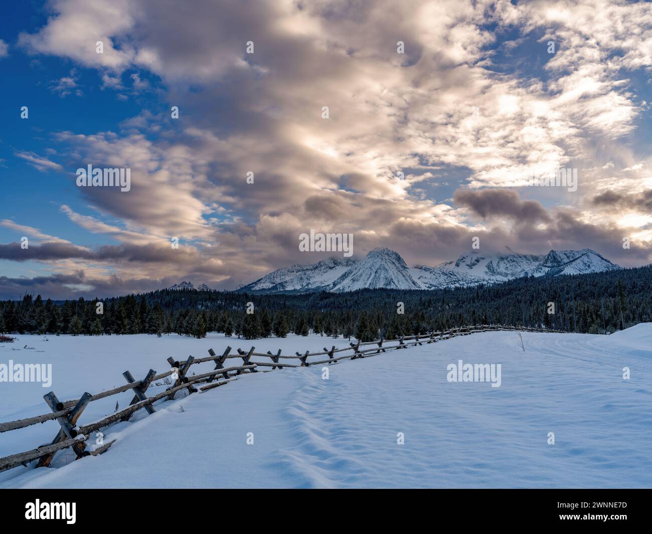 Winter snow covered scene with mountains and pole fence Stock Photo