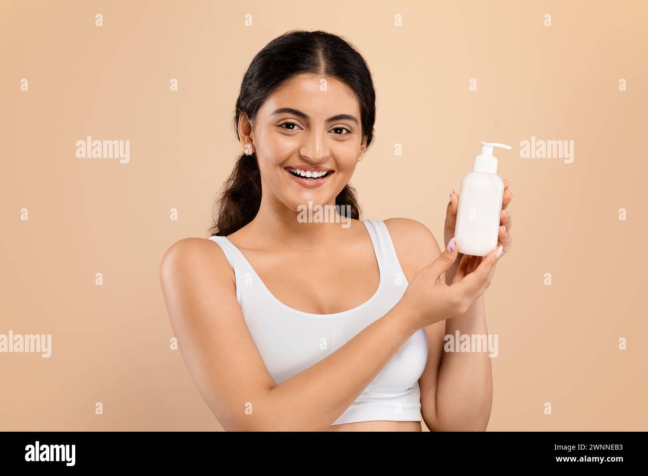 Indian woman with beautiful smile holding white lotion dispenser Stock Photo