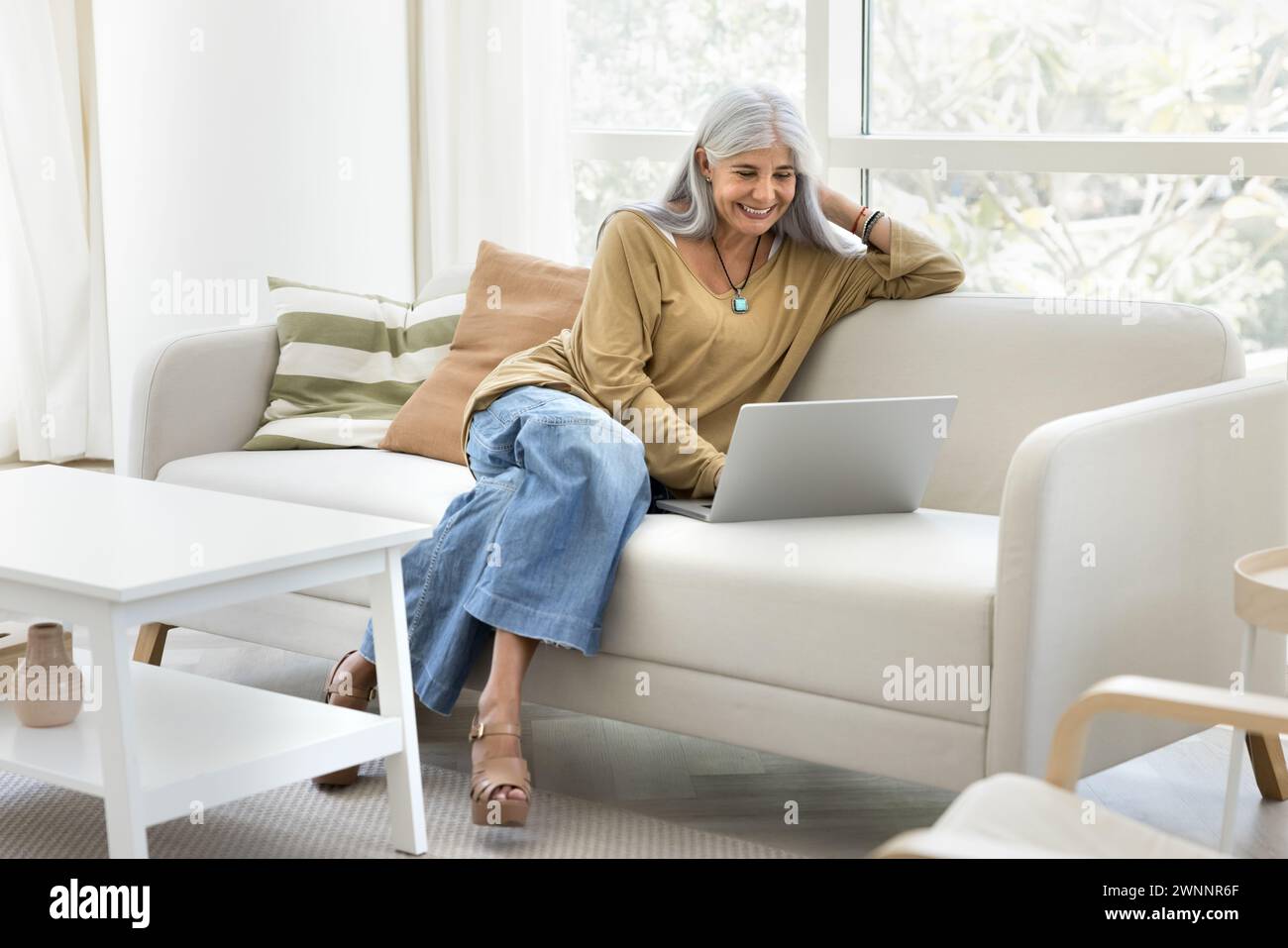 Happy senior elder Latin woman typing on laptop Stock Photo