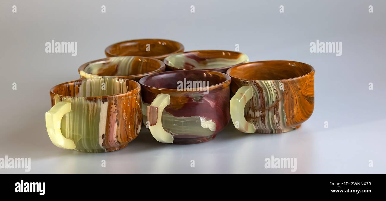 Empty cups made of multi-colored onyx in yellow-orange tones on a white background. Stock Photo