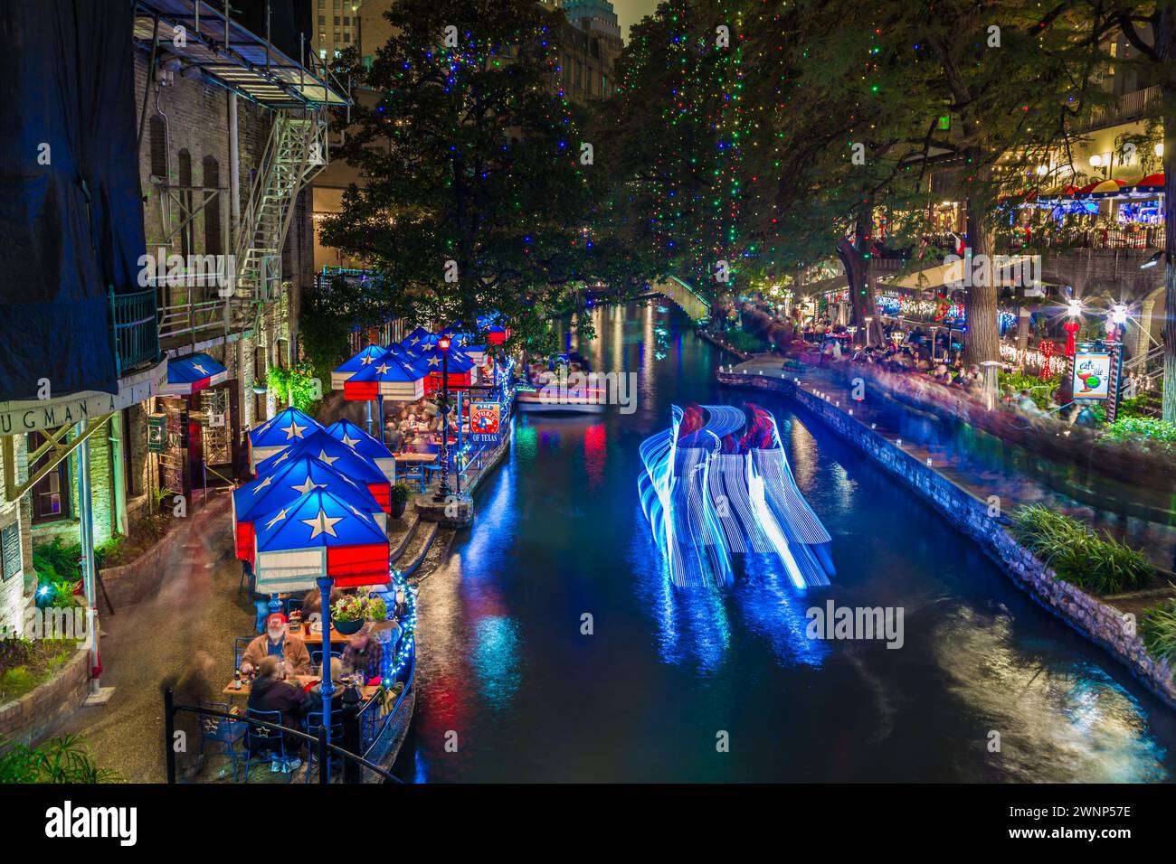 Time lapse photo of a pontoon boat on the San Antonio River at The Republic of Texas restaurant on the River Walk in downtown San Antonio, Texas Stock Photo