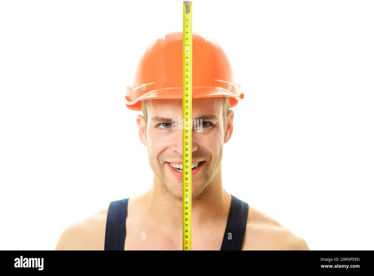 Male builder in safety helmet with construction tape measure. Professional carpenter in construction hard hat with building tool tape measure Stock Photo