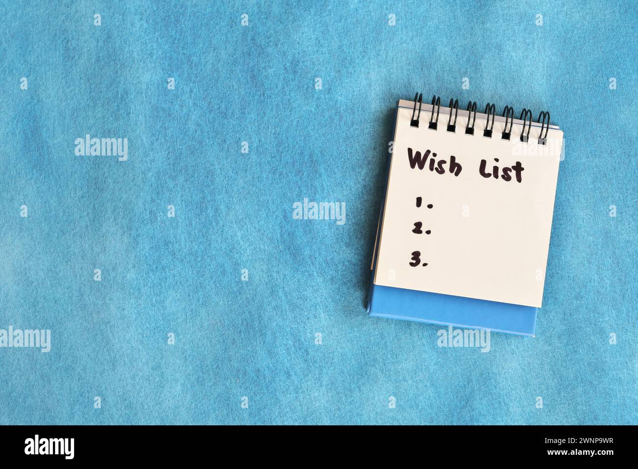 Wish list concept. White note pad isolated on blue background. Stock Photo