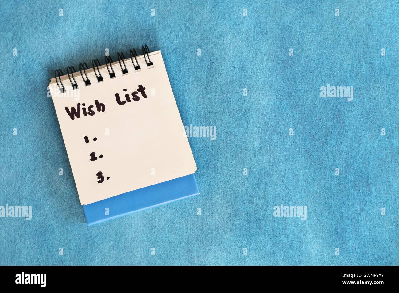 Wish list concept. White note pad isolated on blue background. Stock Photo