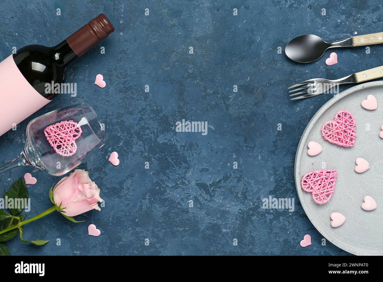 Beautiful table setting with hearts, pink rose and bottle of wine on ...