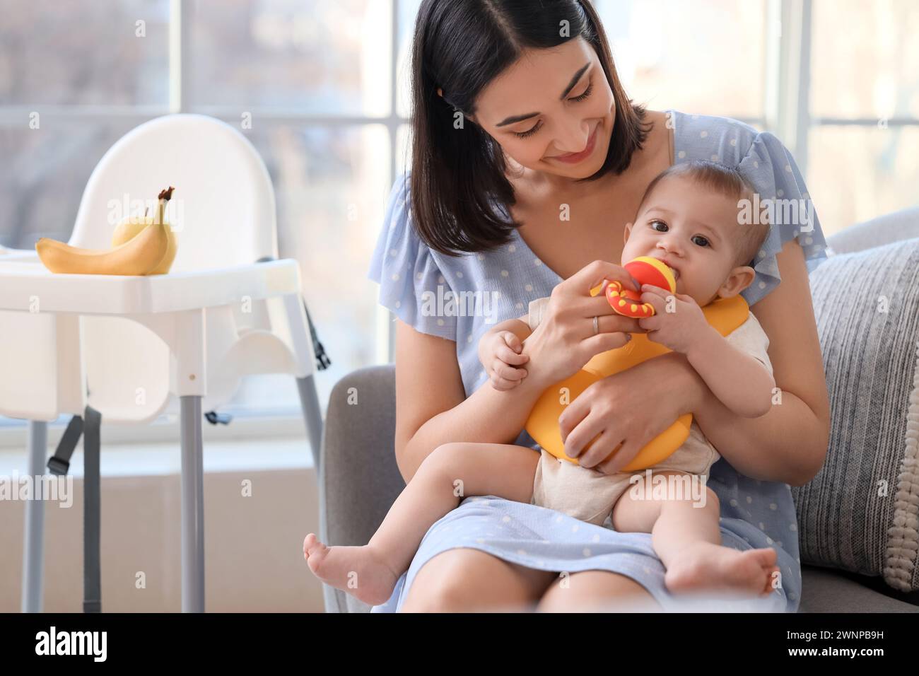 Mother and her little baby with nibbler eating food at home Stock Photo