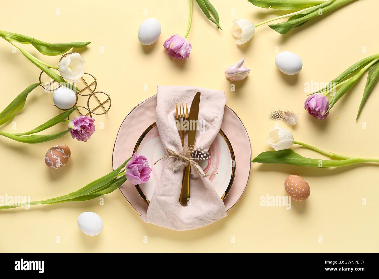 Table setting with Easter eggs and beautiful tulips on yellow ...