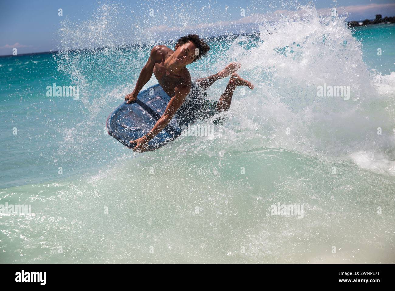 Locals ride the waves on a white sand beach on Hawaii. Stock Photo