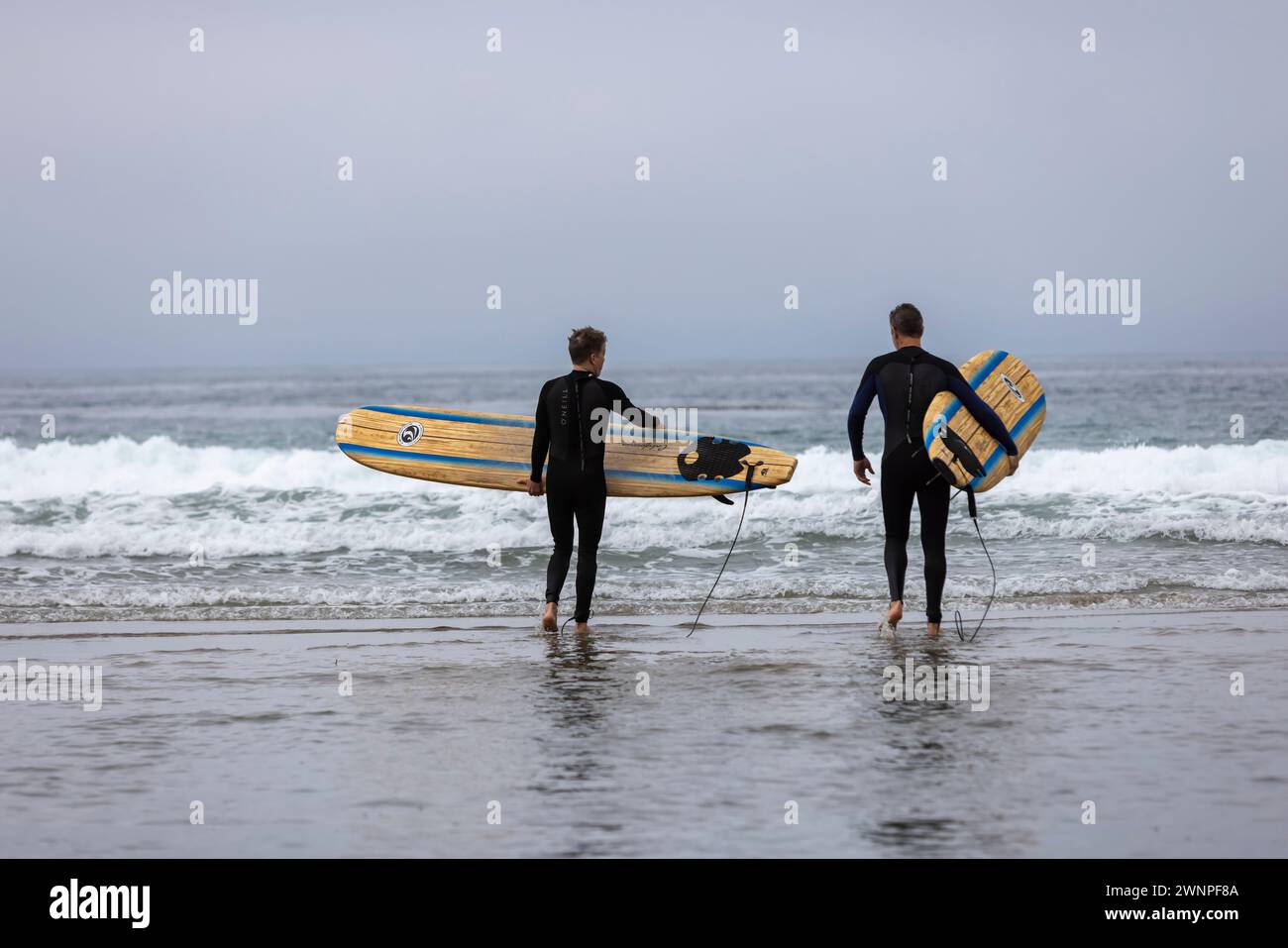Surfers enter the water at Zuma beach in Malibu. Stock Photo