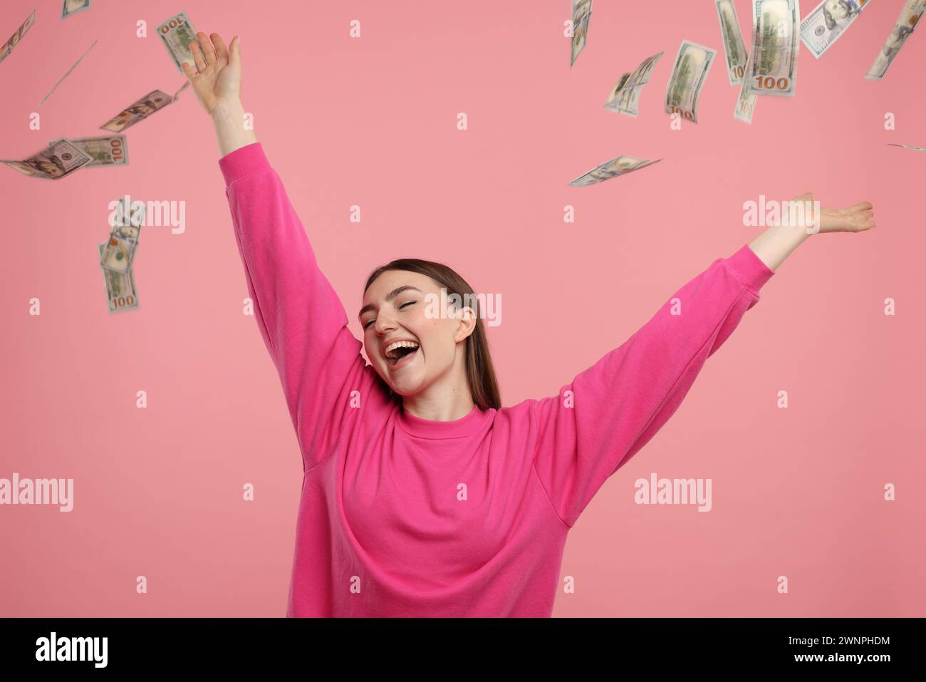 Happy woman under money shower on pink background Stock Photo