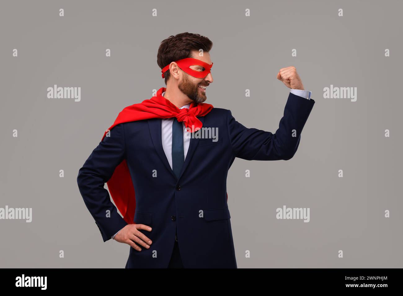 Happy businessman wearing red superhero cape and mask on beige ...