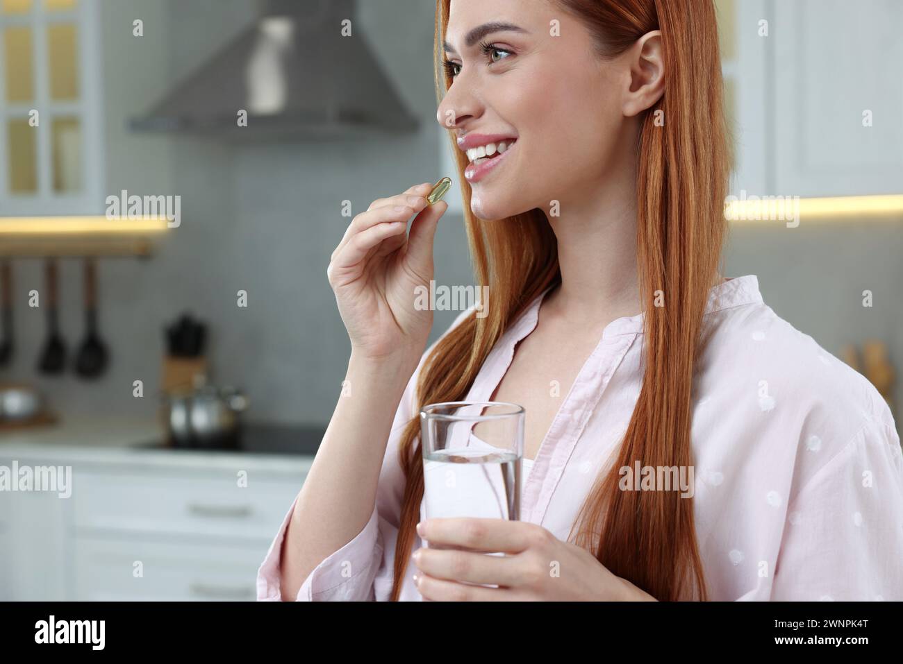 Beautiful young woman taking vitamin pill at home Stock Photo