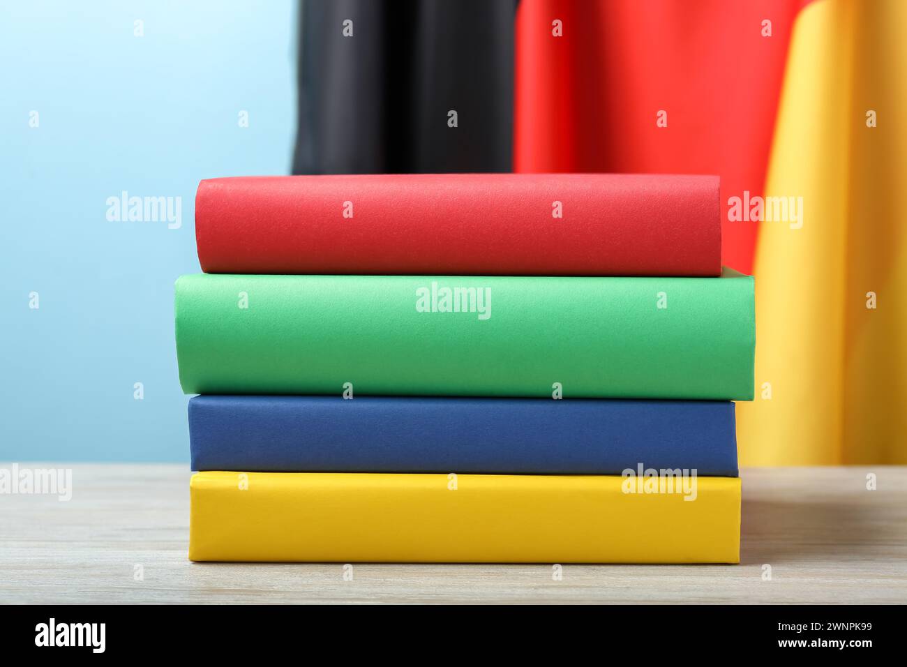 Learning foreign language. Different books on wooden table near flag of Germany Stock Photo