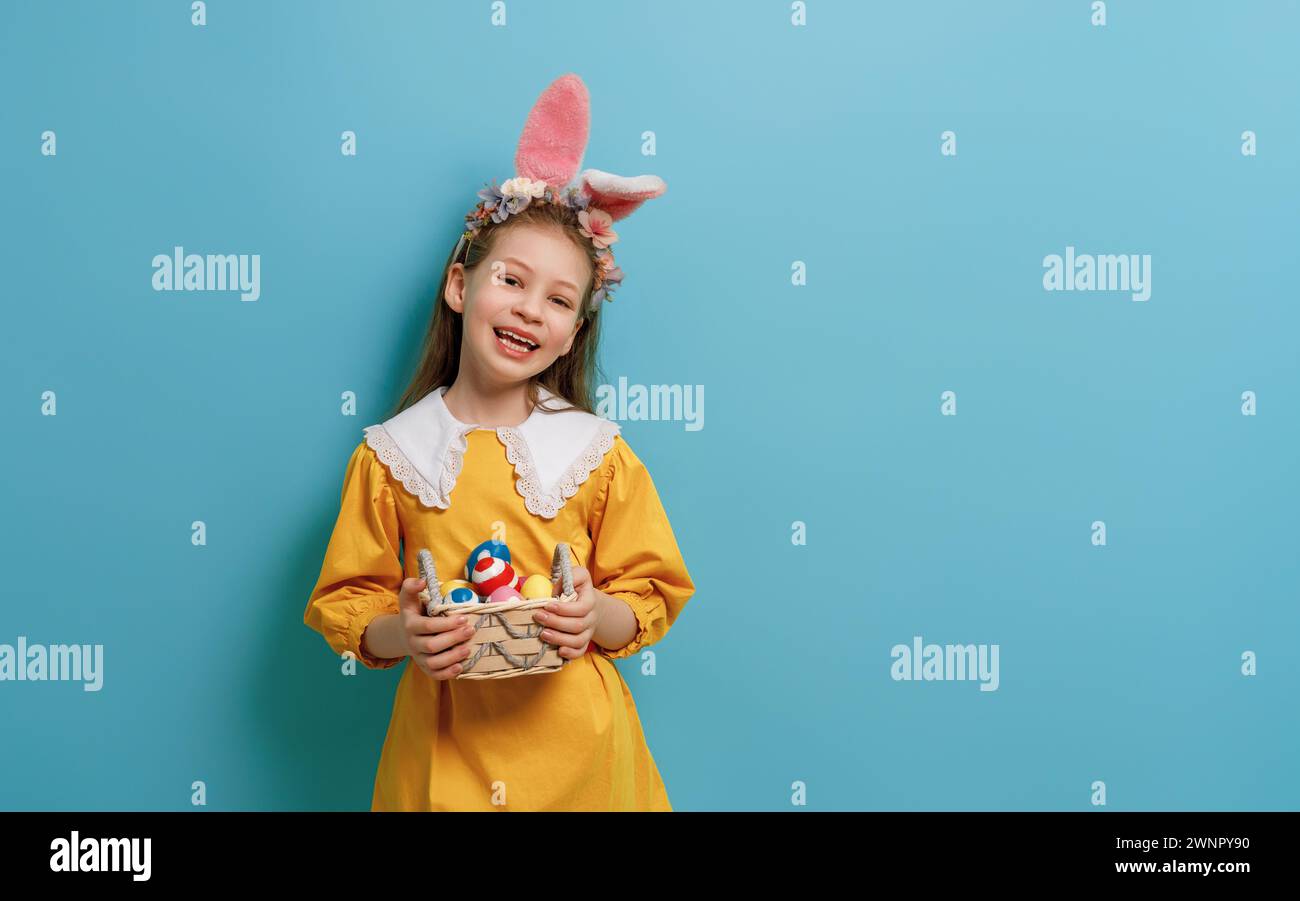 Cute little child wearing bunny ears on Easter day. Girl with painted eggs. Stock Photo