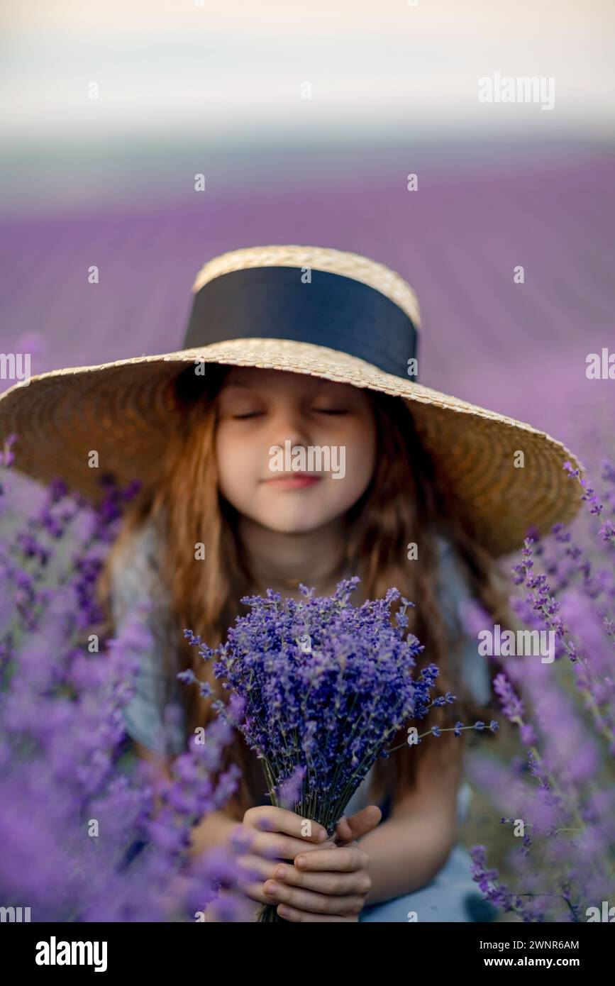 Girl lavender field in a blue dress with flowing hair in a hat stands ...
