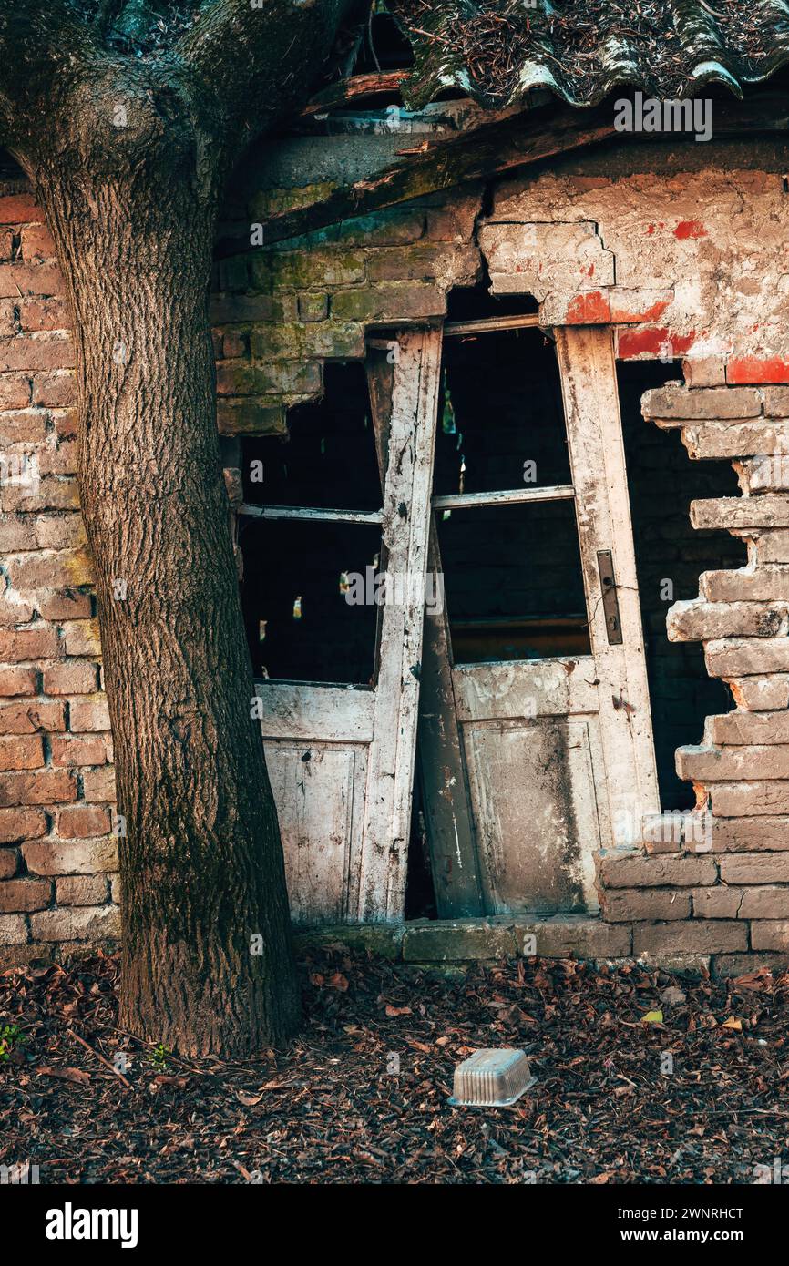 Old ruined house with damaged brick wall and broken doors ready for rundown, vertical image Stock Photo