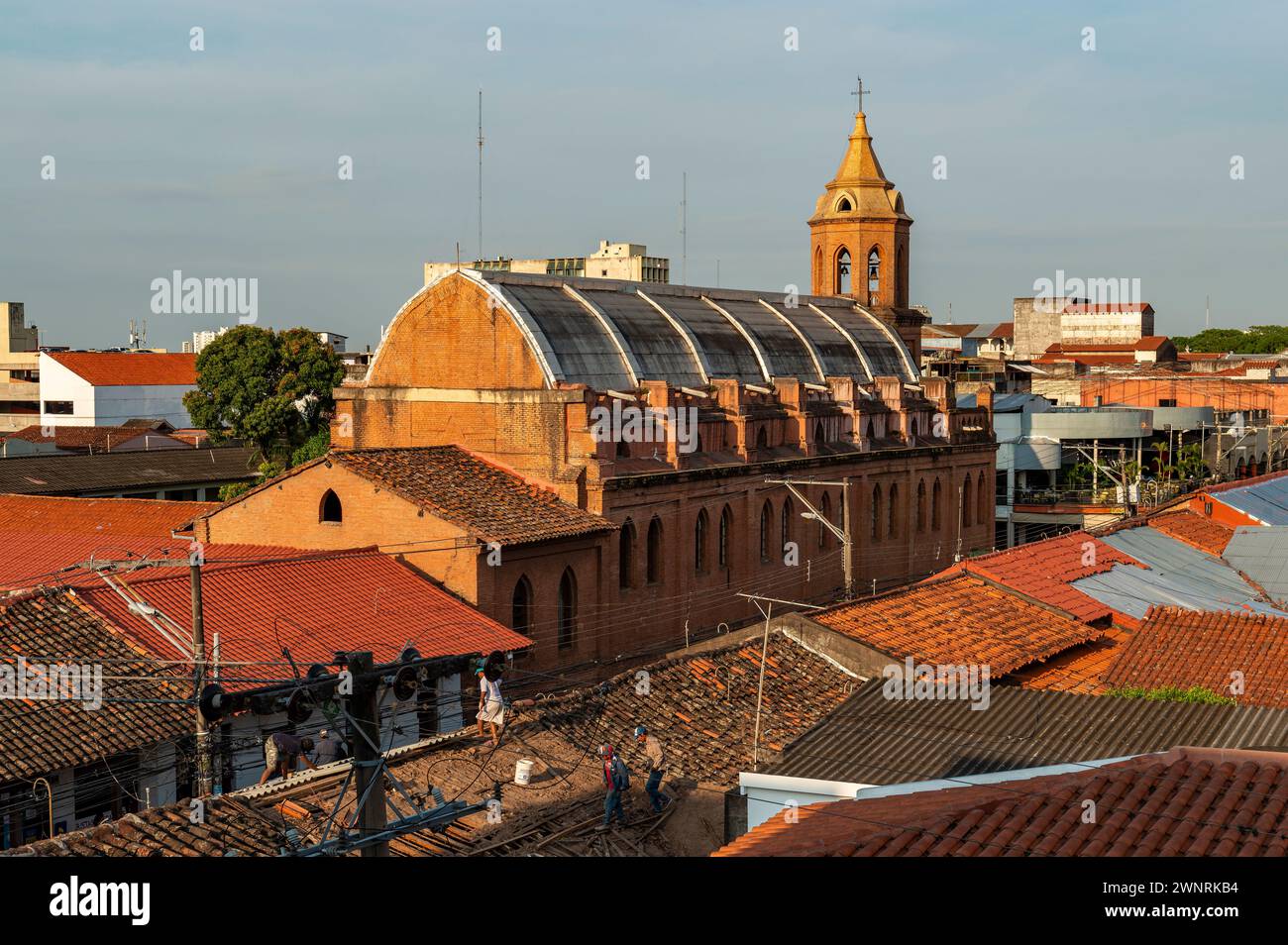 Merced church at sunrise with people working on the roof of a house, Santa Cruz de la Sierra, Bolivia. Stock Photo