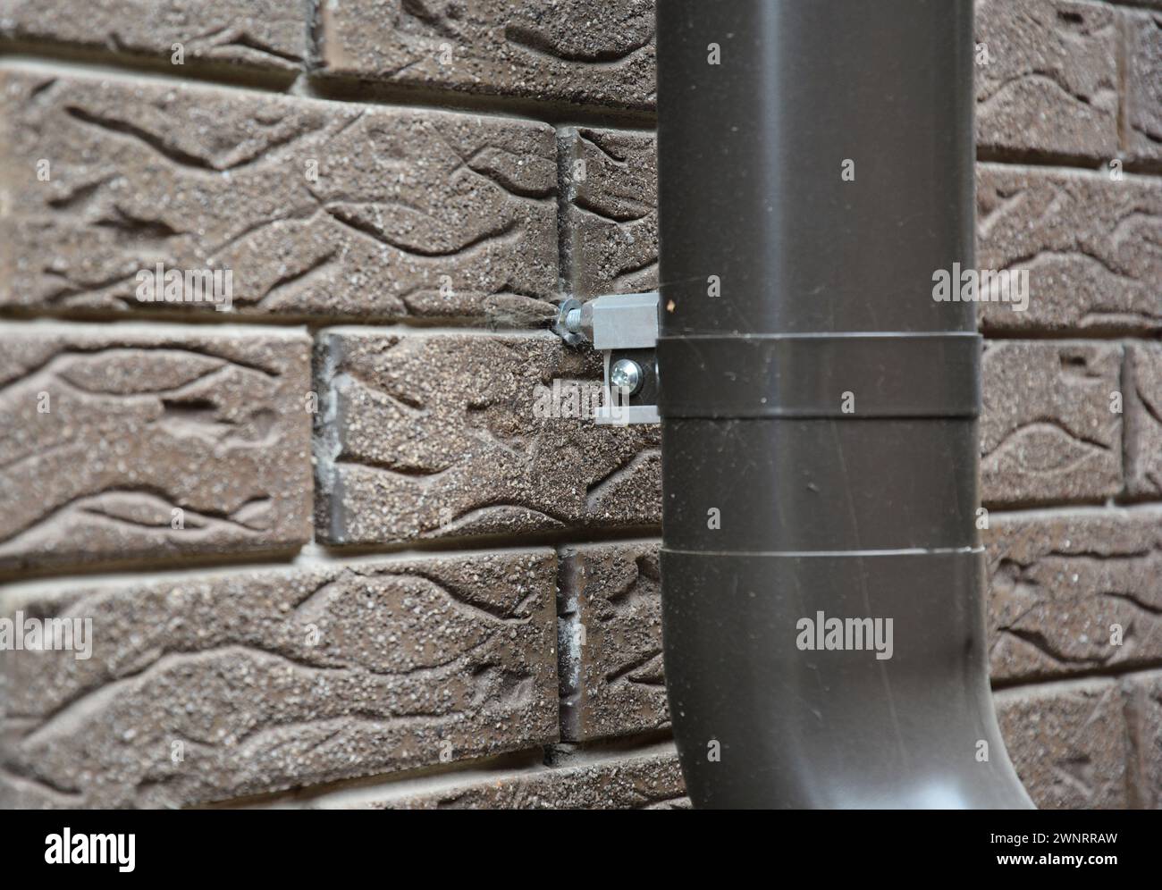 Close up on house rain gutter downspout pipe anchor bolt holder on the