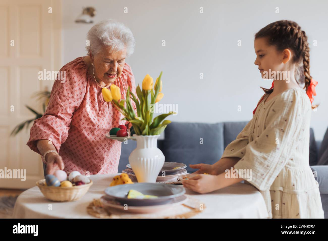 Grandmother with granddaughter setting table for traditional easter