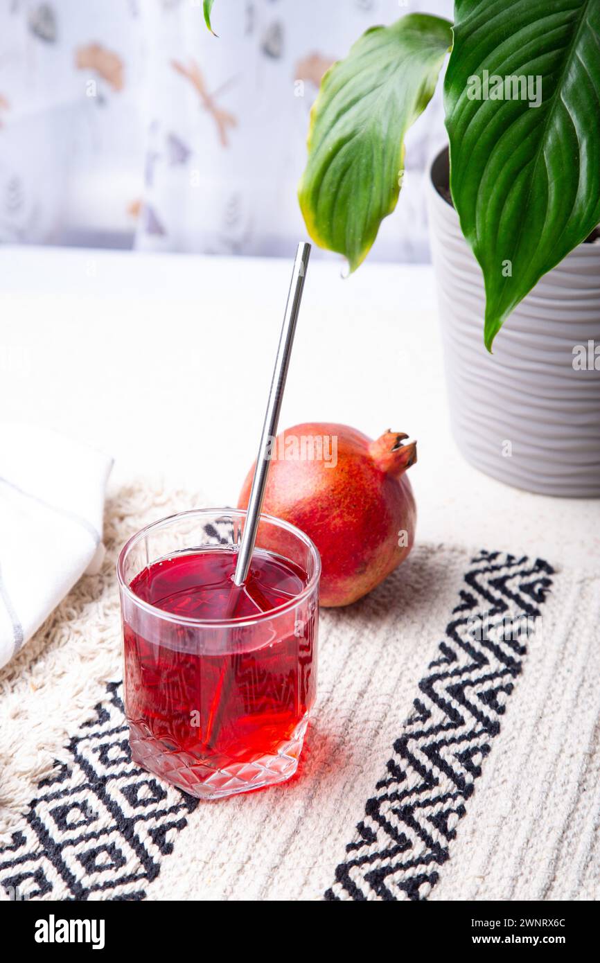 Juice Aesthetics - Pomegranate Refreshment. Natural healthy juice near indoor plant. Stock Photo