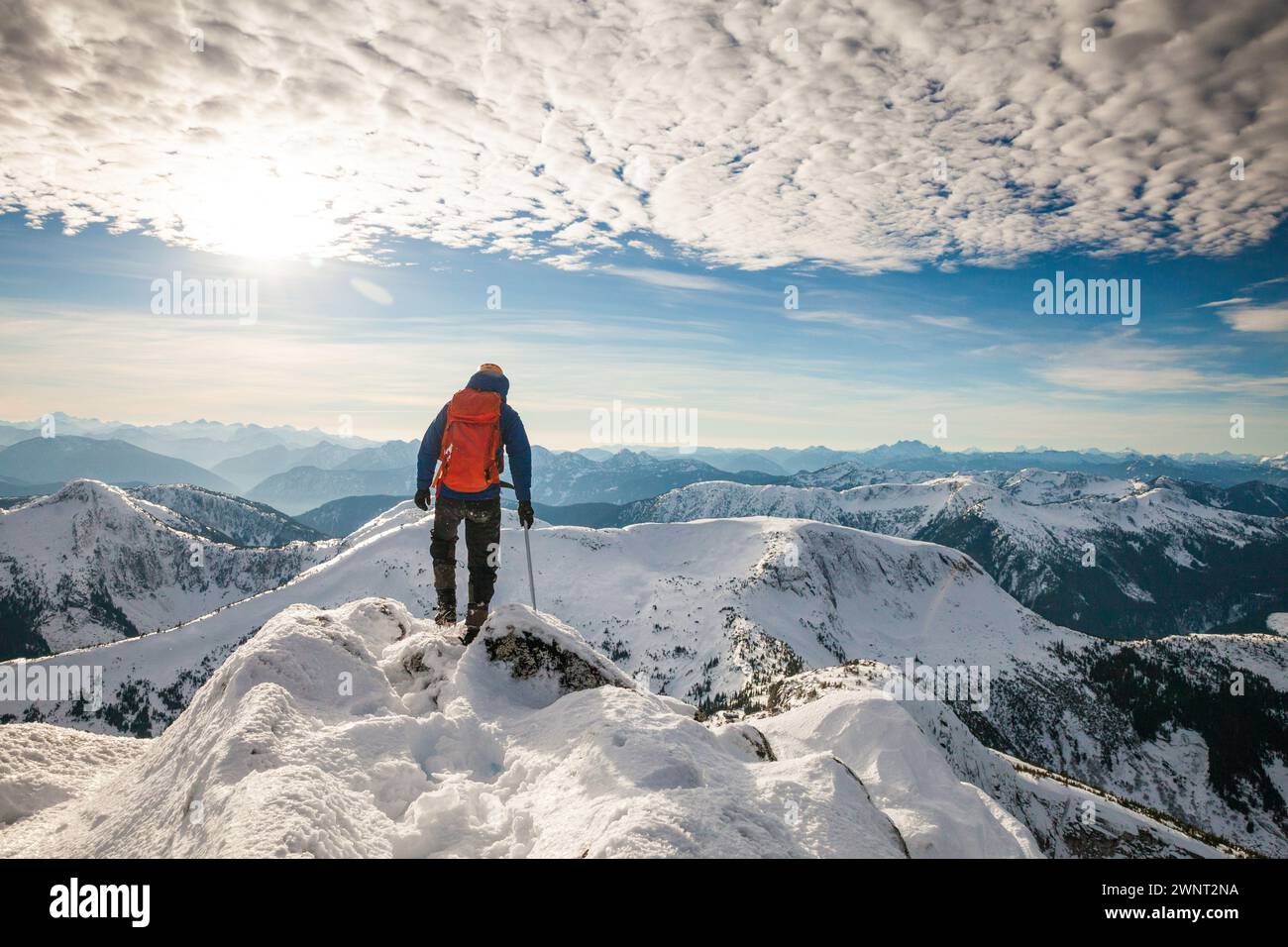 Rear view of successful backpacker standing on mountain summit Stock Photo