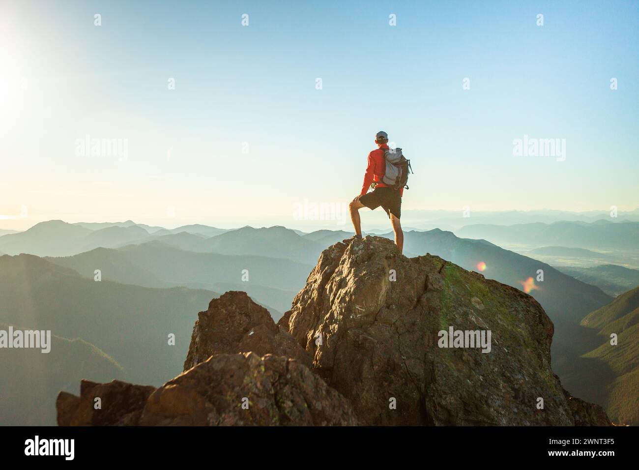 successful man stands on mountain summit at sunset Stock Photo