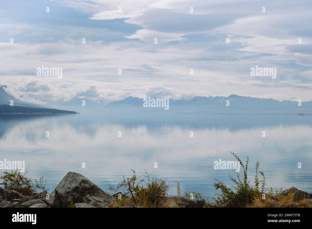 Scenic water reflection of cloudy sky with rocky border Stock Photo