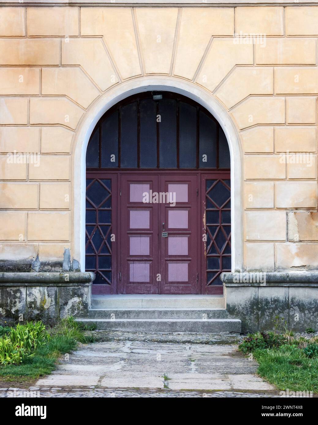 wooden door in the arch entrance on the old facade. exterior with textured wall Stock Photo