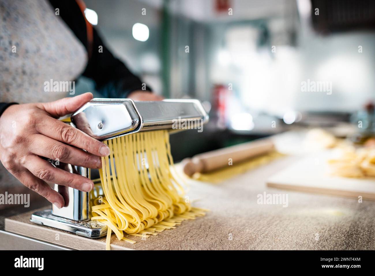 Close up of female hands preparing fresh pasta using traditional machine - Cuisine and food concept Stock Photo