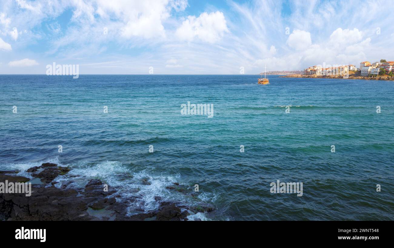 rocks on the seaside of resort town. vacation and leisure background in summertime. bulgarian seascape in late summer. boat on the water in the distan Stock Photo