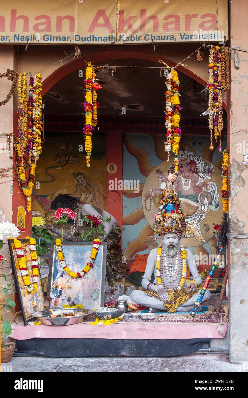 Varanasi, India - February 24, 2024: old sadu painted in white ash is meditatingin an arch of the hostel for religious Hindus in Varanasi is collectio Stock Photo