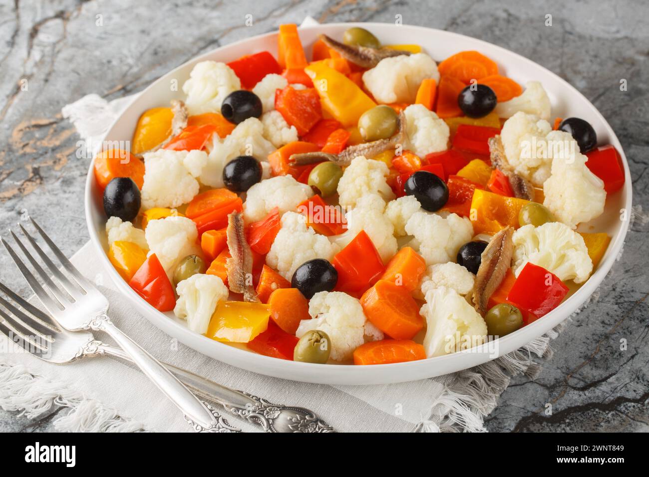 Festive Italian cauliflower salad with giardiniera, olives and anchovies close-up on a plate on the table. Horizontal Stock Photo