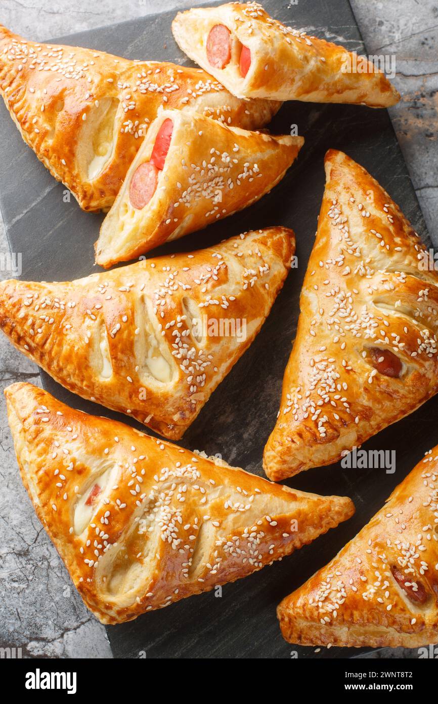 Sausage And Puff Pastry Turnovers closeup on the marble board on the table. Vertical top view from above Stock Photo