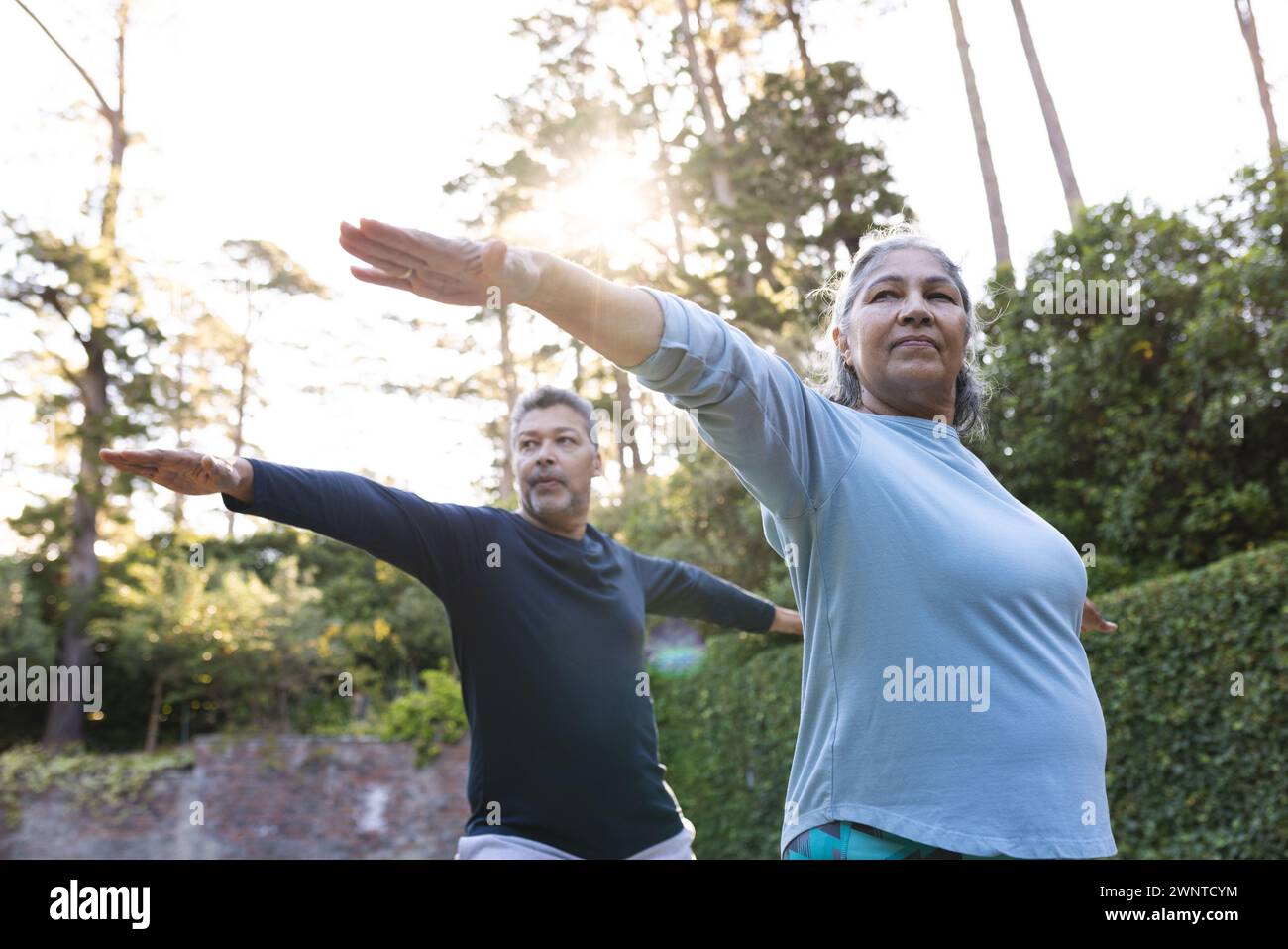 Senior biracial woman and man practice yoga outdoors at home Stock Photo