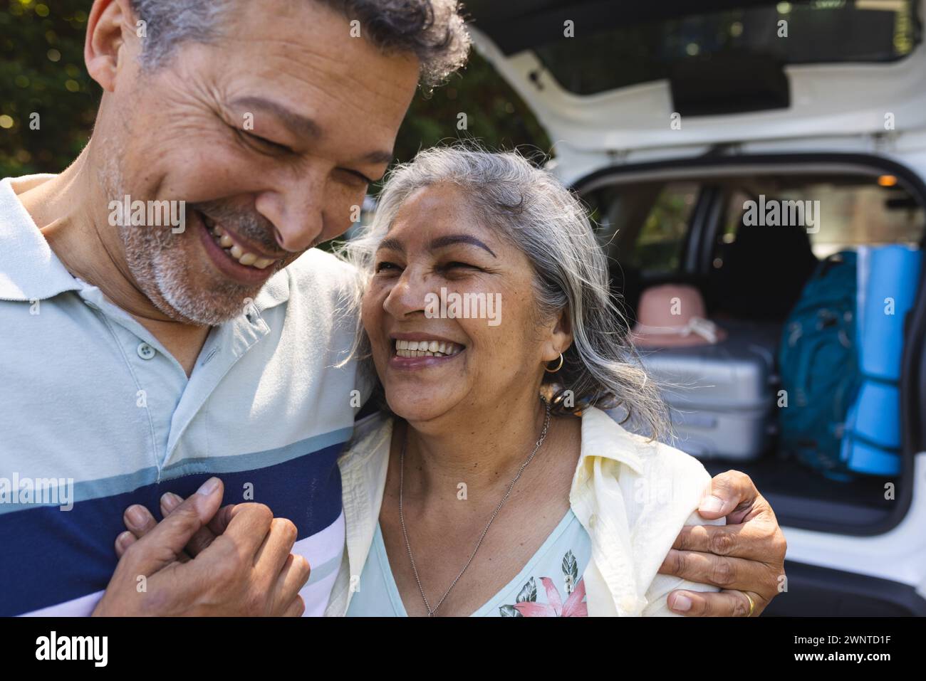 Senior biracial couple shares a joyful moment, with the man embracing the woman Stock Photo
