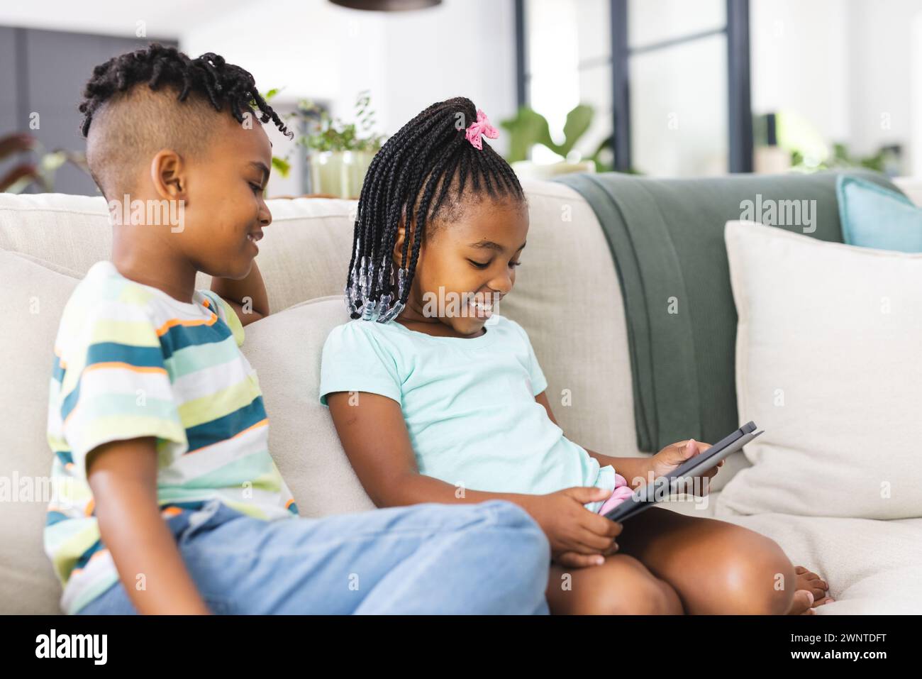 African American sister with braided hair and a brother with a mohawk are using a tablet Stock Photo